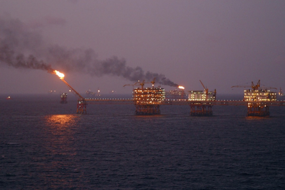 Offshore oil platform with a gas flare at dusk