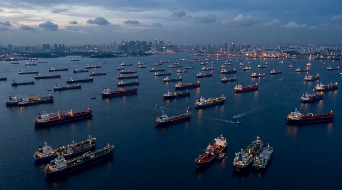 Vessels at anchorage at dusk off Singapore, city skyline beyond